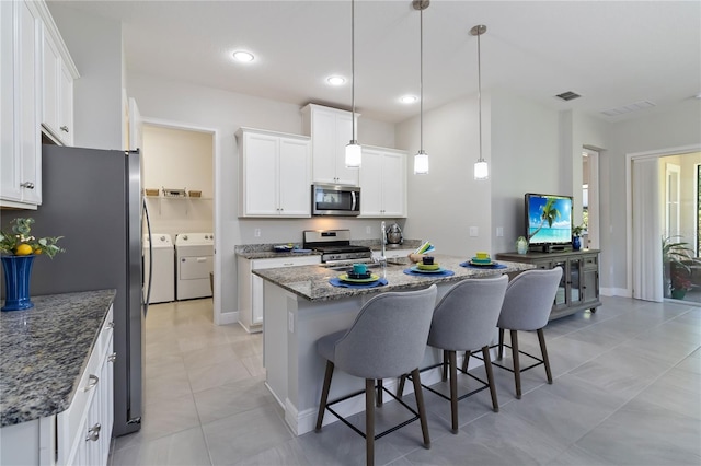 2423 Datura Loop, Saint Cloud, FL 34772 - kitchen with appliances with stainless steel finishes, washer and dryer, a kitchen bar, white cabinets, and recessed lighting