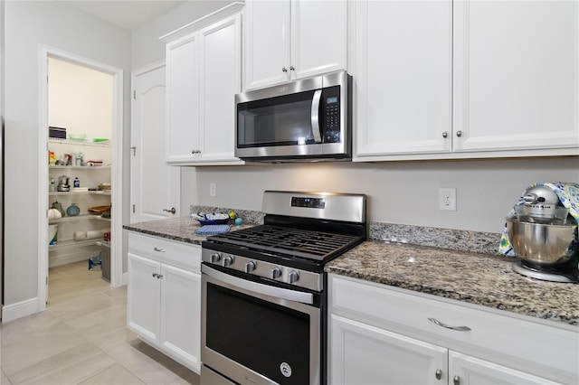 2423 Datura Loop, Saint Cloud, FL 34772 - kitchen featuring stainless steel appliances, dark stone counters, white cabinets, and light tile patterned floors