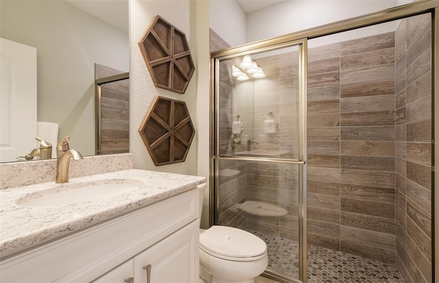 full bathroom featuring a shower stall, toilet, and vanity