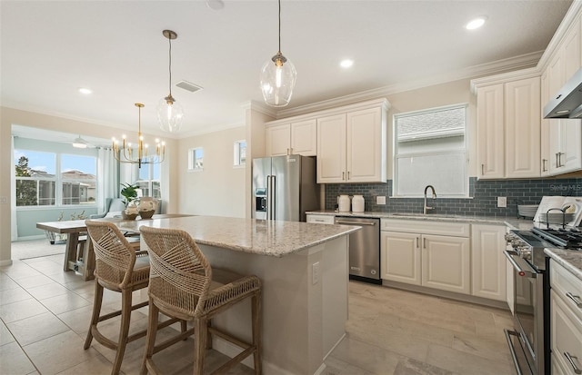 kitchen featuring a sink, visible vents, a kitchen island, ornamental molding, and appliances with stainless steel finishes