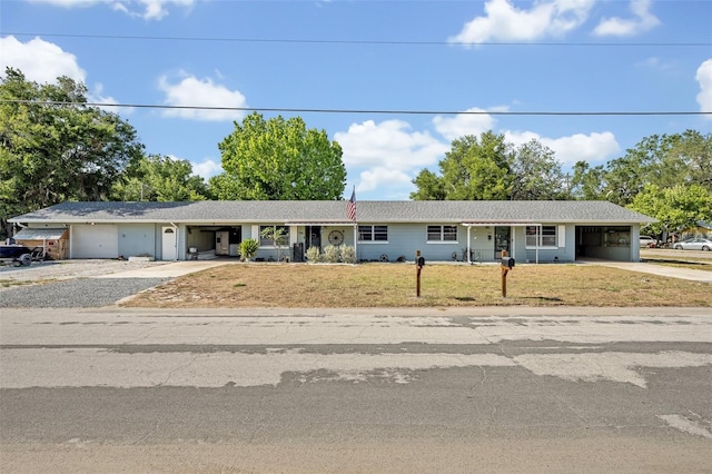 ranch-style home featuring concrete driveway, an attached carport, a garage, and a front lawn