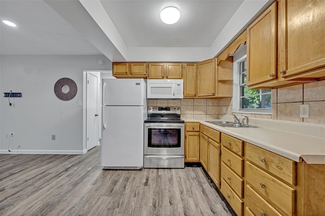 kitchen with decorative backsplash, white appliances, baseboards, a sink, and light wood-style flooring