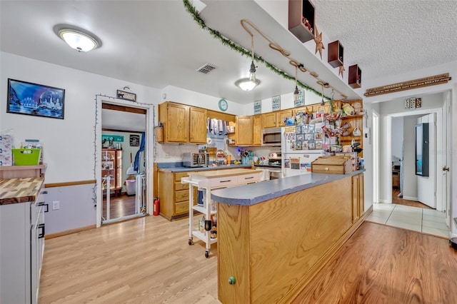 kitchen featuring visible vents, appliances with stainless steel finishes, a toaster, a peninsula, and light wood finished floors