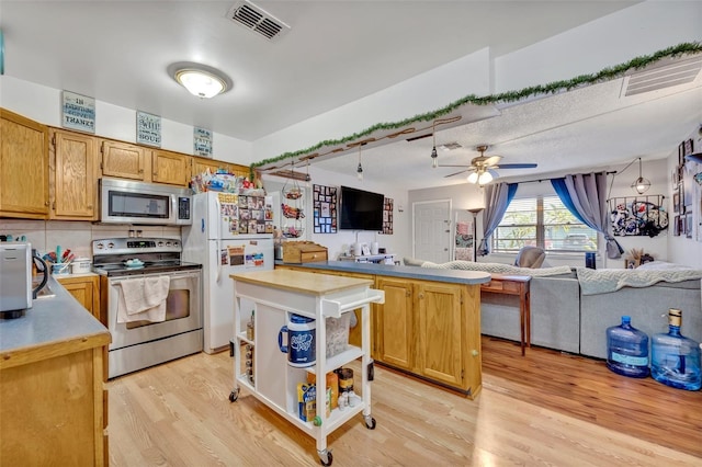 kitchen featuring stainless steel appliances, ceiling fan, open floor plan, and light wood-style flooring