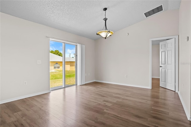 15 Sawfish Ln, Kissimmee, FL 34759 - unfurnished room with a textured ceiling, baseboards, wood finished floors, vaulted ceiling, and visible vents