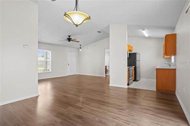 15 Sawfish Ln, Kissimmee, FL 34759 - unfurnished living room with light wood-style floors, a ceiling fan, vaulted ceiling, and a sink