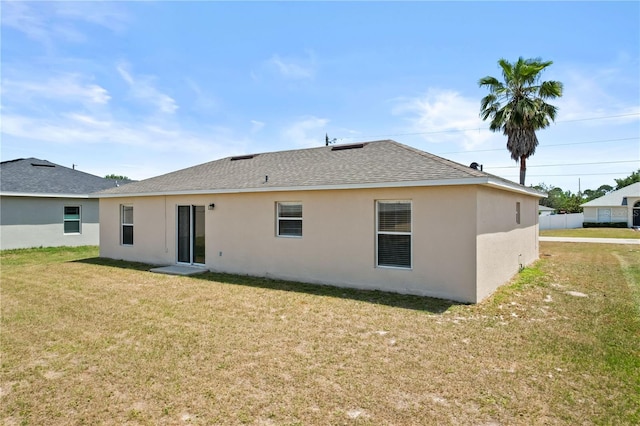 15 Sawfish Ln, Kissimmee, FL 34759 - rear view of property featuring a lawn, a shingled roof, and stucco siding