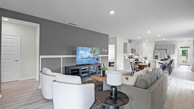 living room featuring recessed lighting, visible vents, baseboards, and light wood-type flooring