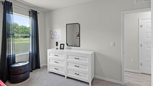 bedroom featuring visible vents, light carpet, and baseboards