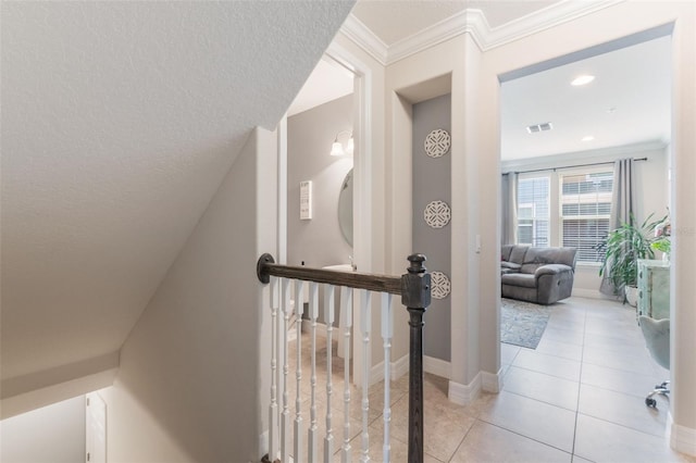 corridor featuring crown molding, light tile patterned flooring, a textured ceiling, and visible vents