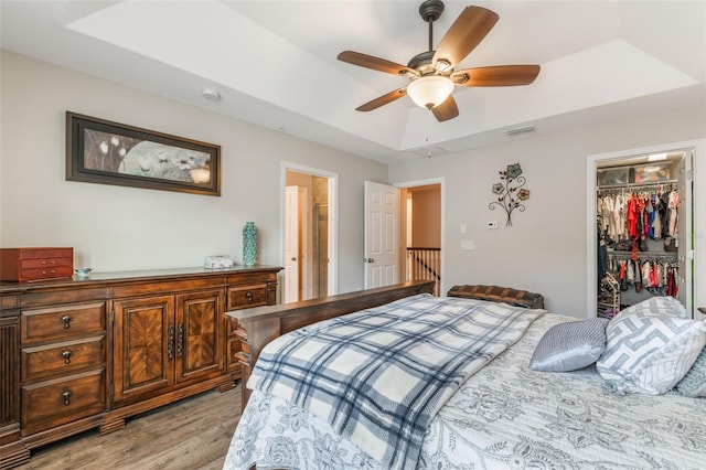 bedroom featuring visible vents, a raised ceiling, a closet, a spacious closet, and light wood-style floors