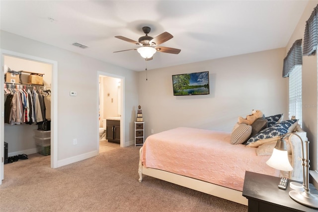 bedroom featuring light colored carpet, a walk in closet, baseboards, visible vents, and a closet