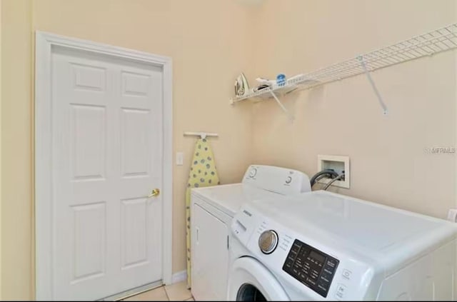 laundry area featuring light tile patterned flooring, washing machine and clothes dryer, and laundry area