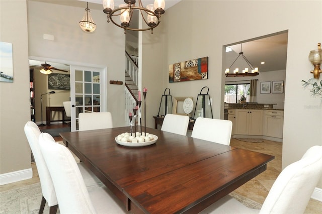 dining space featuring baseboards, stairs, a towering ceiling, and ceiling fan with notable chandelier