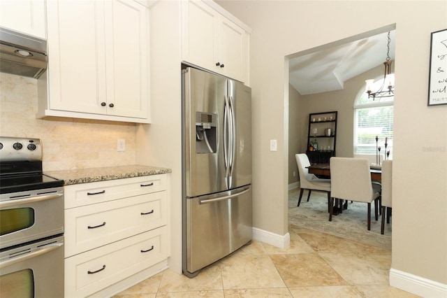 kitchen featuring an inviting chandelier, decorative backsplash, under cabinet range hood, light stone counters, and appliances with stainless steel finishes