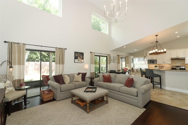 living area featuring dark wood-style flooring, a high ceiling, a notable chandelier, and recessed lighting