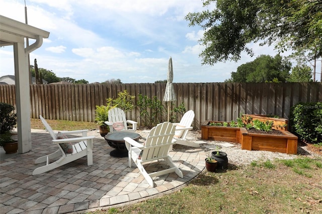 view of patio featuring fence, a garden, and an outdoor fire pit