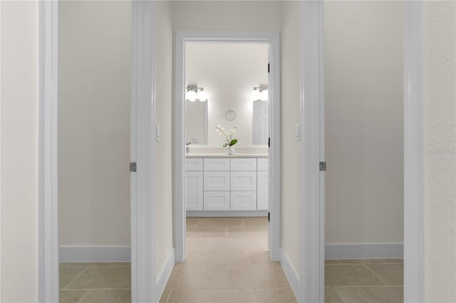 corridor featuring baseboards and light tile patterned flooring