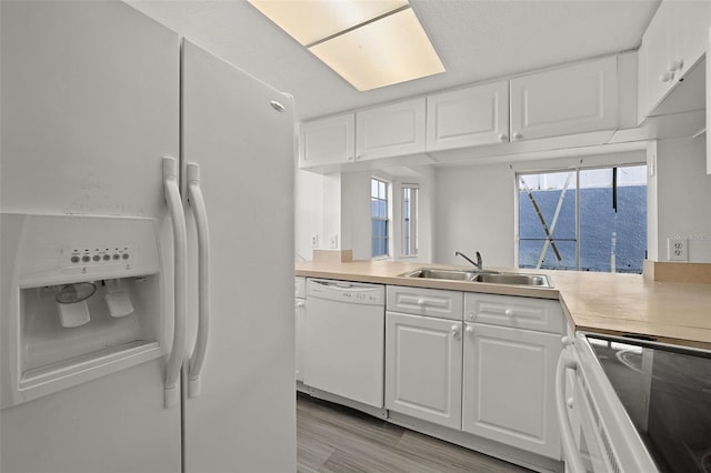 kitchen with a sink, white cabinetry, white appliances, and light countertops