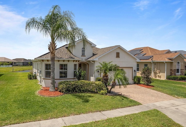 view of front of home with a garage, decorative driveway, a front lawn, and stucco siding
