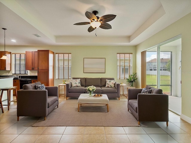 living room with a wealth of natural light, a tray ceiling, and visible vents