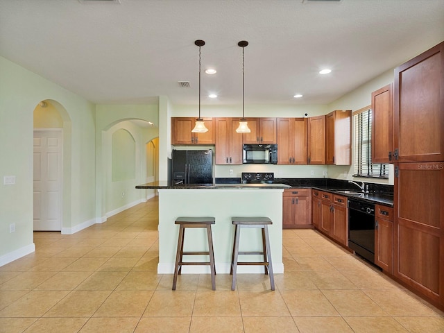 kitchen with dark countertops, a center island, black appliances, and a breakfast bar area