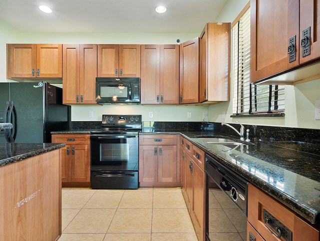 kitchen featuring recessed lighting, a sink, dark stone counters, and black appliances