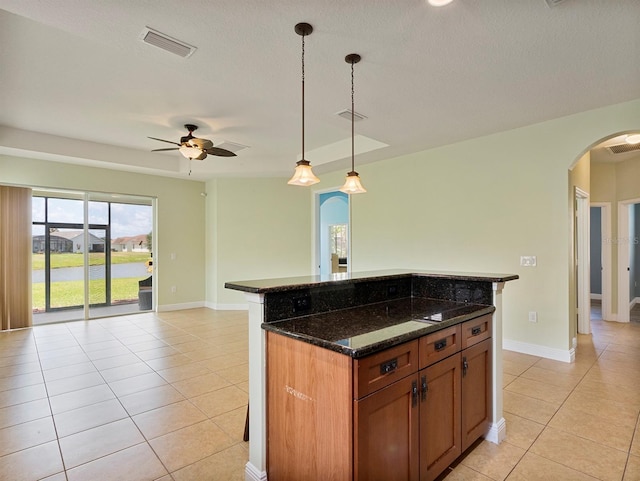 kitchen featuring visible vents, open floor plan, arched walkways, light tile patterned floors, and decorative light fixtures