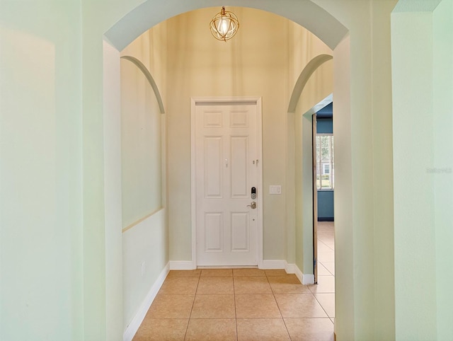 foyer entrance with light tile patterned floors, arched walkways, and baseboards