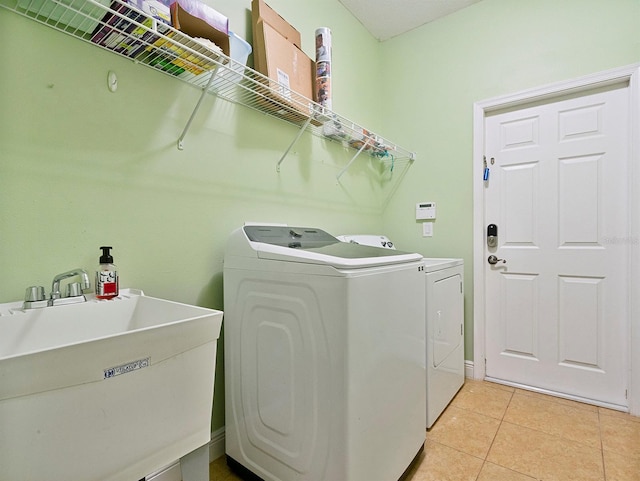 clothes washing area featuring a sink, light tile patterned floors, laundry area, and washer and dryer