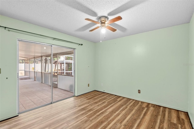 unfurnished room with baseboards, ceiling fan, a textured ceiling, and wood finished floors