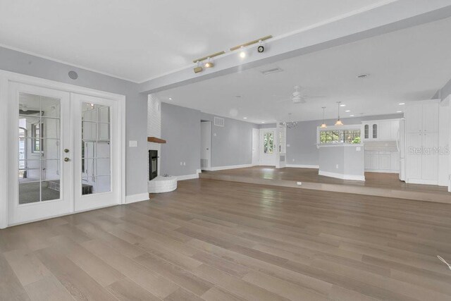 3605 Pershing Ave, Orlando, FL 32812 - unfurnished living room with french doors, light wood-style flooring, ceiling fan, baseboards, and a brick fireplace