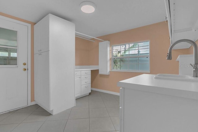 3605 Pershing Ave, Orlando, FL 32812 - kitchen with a sink, white cabinetry, baseboards, light countertops, and light tile patterned floors
