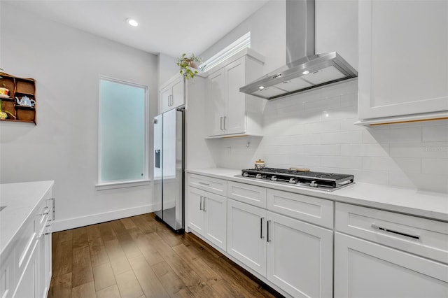 kitchen featuring stainless steel gas stovetop, refrigerator with ice dispenser, wall chimney exhaust hood, light countertops, and white cabinets