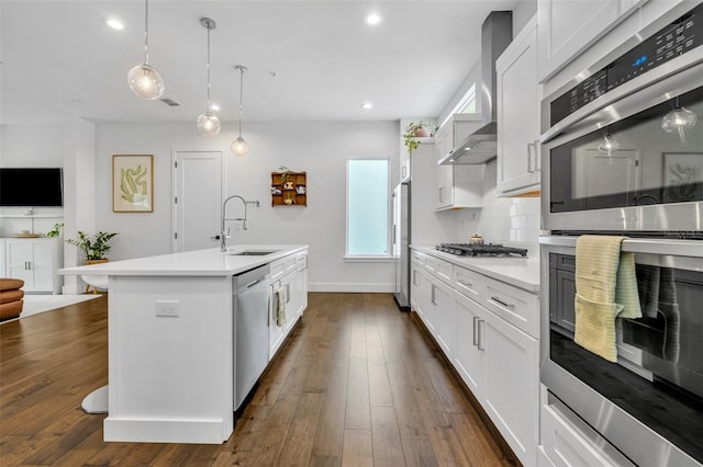 kitchen featuring wall chimney range hood, light countertops, stainless steel appliances, and a sink
