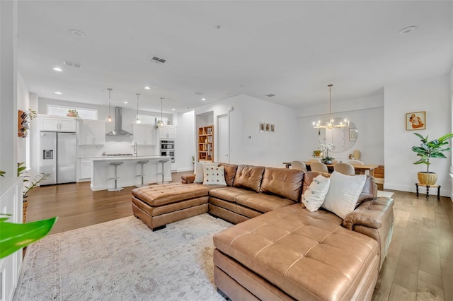 living room with a chandelier, visible vents, light wood-style flooring, and recessed lighting