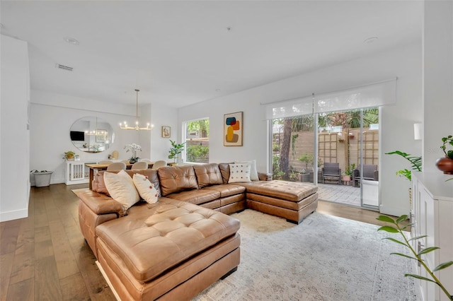 living room with visible vents, wood finished floors, and a notable chandelier