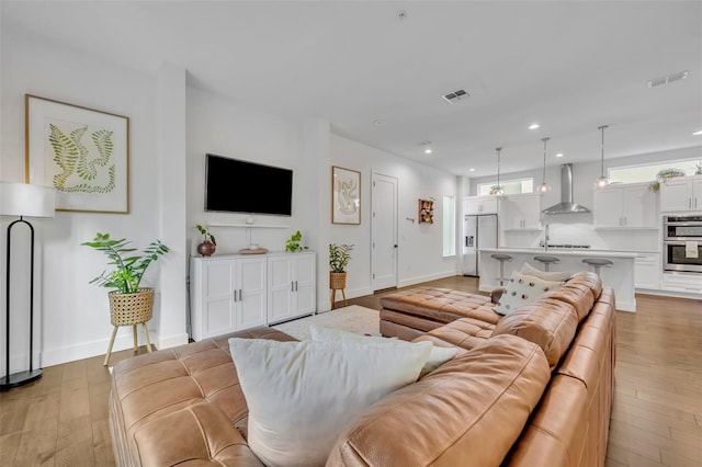 living room featuring recessed lighting, baseboards, visible vents, and light wood-style floors