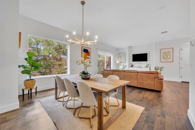 dining room featuring an inviting chandelier, plenty of natural light, dark wood-type flooring, and baseboards
