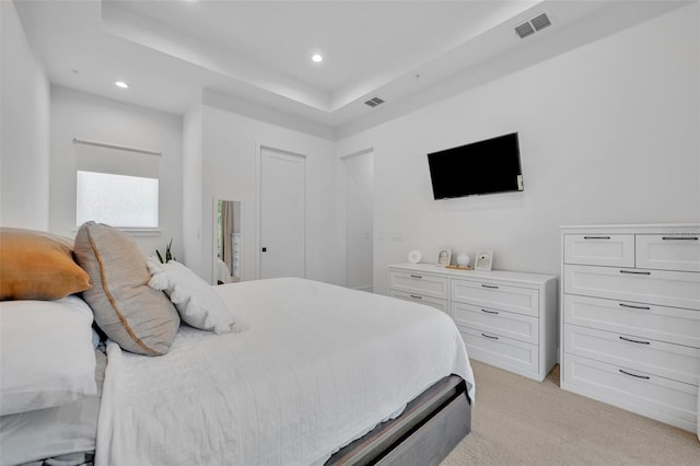 bedroom with light colored carpet, visible vents, a raised ceiling, and recessed lighting