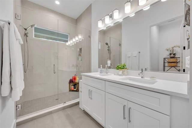 bathroom with a shower stall, tile patterned floors, double vanity, and a sink