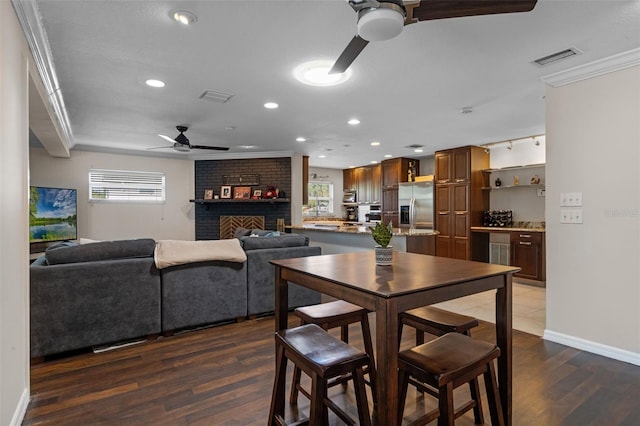 4118 Teriwood Ave, Orlando, FL 32812 - dining area featuring a ceiling fan, visible vents, crown molding, a fireplace, and dark wood finished floors