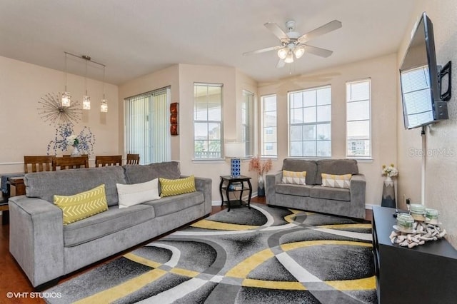 living area featuring baseboards, plenty of natural light, and a ceiling fan