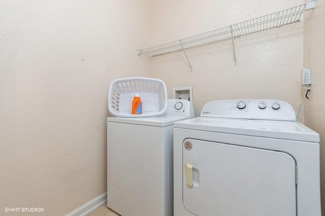 clothes washing area featuring baseboards, laundry area, and washing machine and clothes dryer