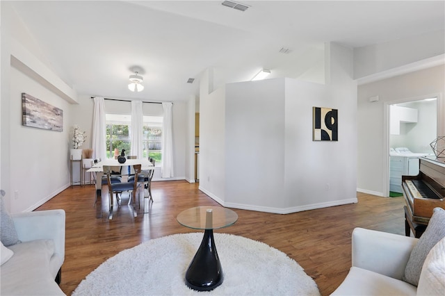 living room featuring visible vents, baseboards, and wood finished floors