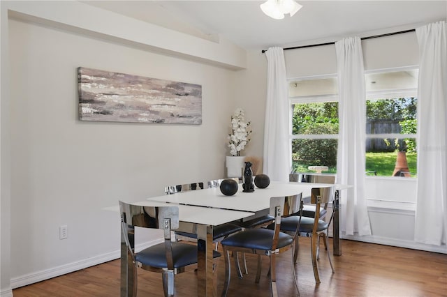 dining space with baseboards, vaulted ceiling, and wood finished floors