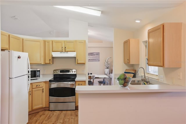 kitchen featuring a peninsula, light brown cabinets, under cabinet range hood, a sink, and appliances with stainless steel finishes