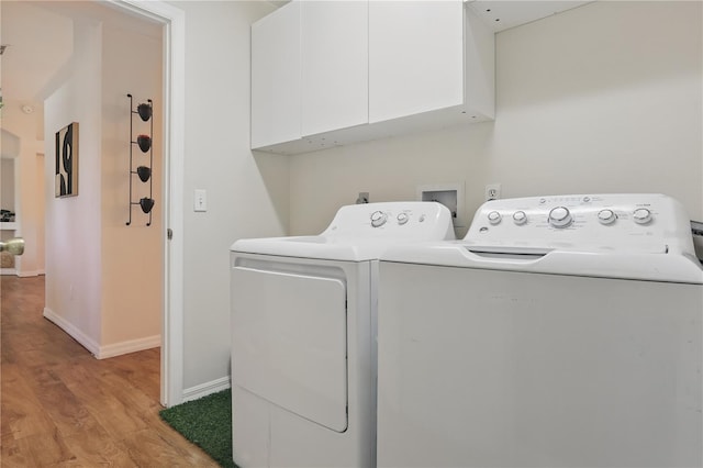 clothes washing area with cabinet space, separate washer and dryer, baseboards, and light wood finished floors