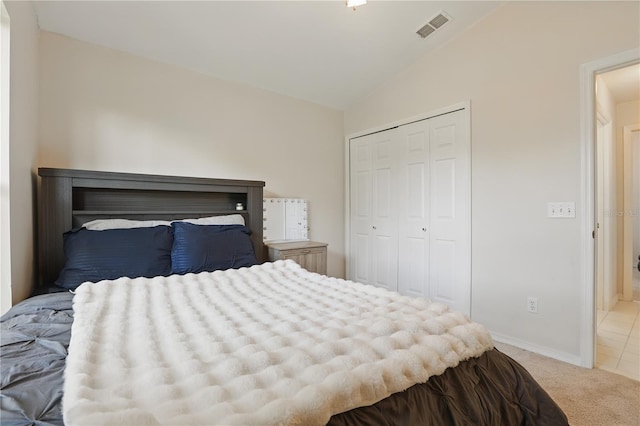 bedroom featuring visible vents, a closet, baseboards, light colored carpet, and vaulted ceiling