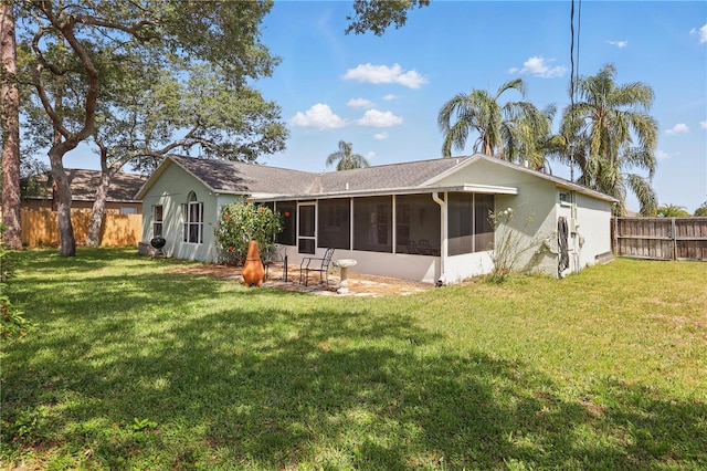 rear view of house with a fenced backyard, a yard, stucco siding, and a sunroom